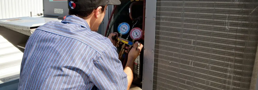 HVAC technician servicing a condenser unit in Ojai